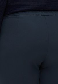 Dark navy stretch fabric pants with a smooth texture, featuring a fitted design and elastic waistband, visible seam details.
