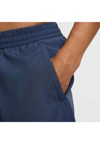 Granatowe szorty sportowe z elastycznym paskiem w talii, bocznymi kieszeniami i gładką tkaniną, charakteryzujące się nowoczesnym designem i praktycznym dopasowaniem.