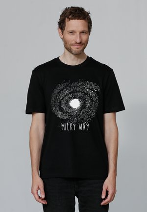 Zwarte T-shirt met een spiraalgalaxie graphic in wit en de tekst "MILKY WAY" onderaan. Katoenen materiaal, ronde hals, korte mouwen.