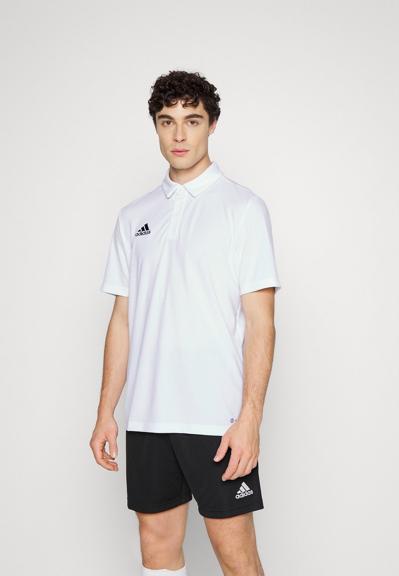 Hvid polo T-shirt lavet af letvægtsstof, med en tre-knap knappesystem og sort Adidas-logo på venstre bryst, parret med sorte shorts.