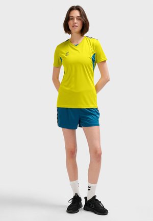Gul sports T-shirt med blå detaljer, parret med teal shorts. Begge beklædningsgenstande har et sportyt design og letvægtsstof.