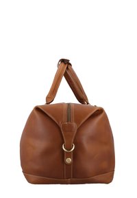 Brązowa skórzana torba podróżna o miękkiej strukturze, z górnym uchwytem, złotymi akcentami, wyraźnym szyciem i zamkiem błyskawicznym na górze.