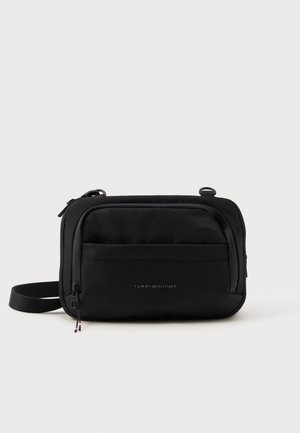 Schwarze Umhängetasche aus strukturiertem Stoff mit einem Hauptfach mit Reißverschluss, einer Vordertasche und verstellbarem Schultergurt. Mit dem Tommy Hilfiger-Logo.