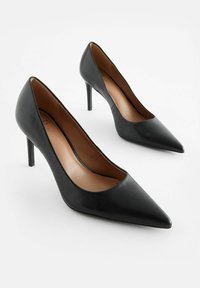 Zapatos de tacón negros de piel con punta afilada y una silueta elegante. Cuentan con un tacón alto y delgado y un forro interior suave para mayor comodidad.