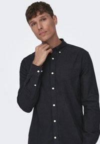 Donkerblauwe, langärmige overhemd met een klein borstzakje, witte knopen en een kraag. Zachte stofstructuur, slim fit.