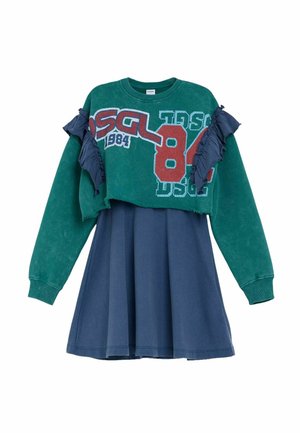 Grünes kurzes Sweatshirt mit rotem und weißem Text "DSGL 84 1984" und gerafften marineblauen Details, kombiniert mit einem marineblauen Rockkleid.