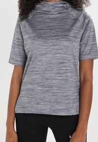 Top deportivo gris de manga corta con un patrón de rayas texturizado y cuello alto. Presenta mangas raglán y un corte relajado.