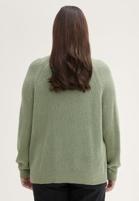 Grüner, gerippter Strickpullover mit lockerer Passform und langen Ärmeln, ausgestattet mit einem runden Halsausschnitt und einem leicht abgerundeten Saum auf der Rückseite.
