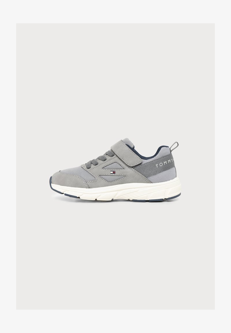 Γκρι και λευκό sneaker χαμηλής κοπής με κορδόνια και λουράκι Velcro, λεπτομέρειες από δίχτυ και το λογότυπο Tommy Hilfiger στο πλάι και στη φτέρνα.