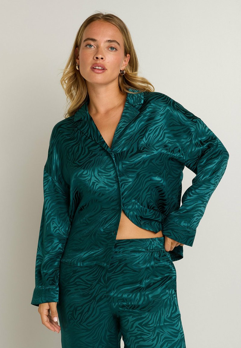 Ensemble de pyjama en satin teal avec un motif zèbre, comprenant une chemise à col avec une découpe à l'avant et des manches longues, associée à un pantalon à taille élastique.