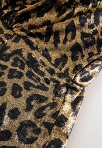 Leopard print fabric in gold and black with a shiny texture. Features dark spots on a metallic gold background. Pattern covers the surface.