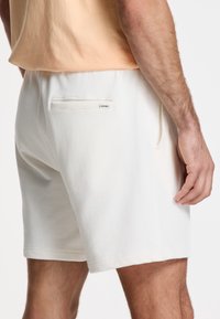 Lysfarvede bomuldsshorts med en afslappet pasform, der har sidelommer og en baglomme med lap. Blød tekstur og enkle designelementer.
