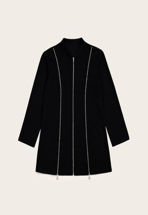 Manteau noir à manches longues, avec une fermeture éclair à l'avant et des accents en chaîne argentée. Il est doté d'un col et d'une coupe droite, avec un design minimaliste.