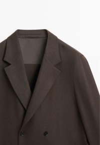 Brązowa marynarka dwurzędowa z wyciętym klapami i wyprofilowanymi ramionami. Gładka tekstura z czarnymi guzikami i minimalistycznym wzornictwem.