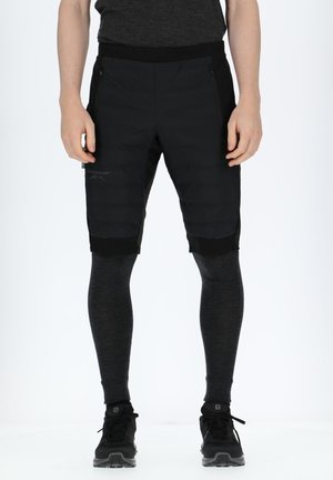 Black hybrid shorts feature a puffy-textured front and solid black back. Paired with fitted dark gray leggings and black athletic shoes.