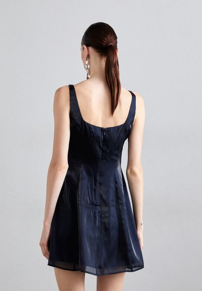 Navy blauwe satin jurk met een getailleerde bodice, A-lijn rok en brede schouderbanden. Beschikt over een ritssluiting aan de achterkant en een zachte textuur.