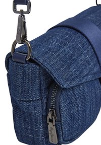 Modrá denimová crossbody taška s texturovaným tkaným designem, klopovým uzávěrem, přední kapsou na zip a kovovými akcenty.