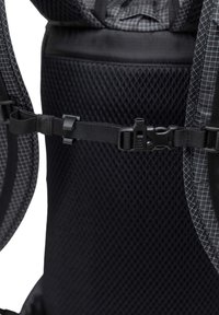 Sac à dos noir en matériau mesh, présentant un motif en grille. Inclut des sangles réglables et des fermetures robustes noires pour un maintien sécurisé.