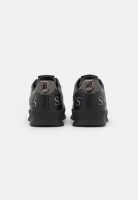 Schwarze Sneakers mit einem eleganten Design, ausgestattet mit einem matten Finish, strukturierten Akzenten und einem erhabenen "SABARUS"-Logo in Silber und Pink auf der Ferse.