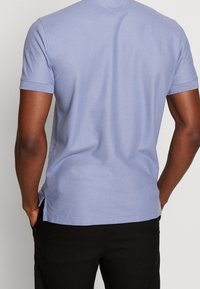 Ljusblå kortärmad t-shirt, tillverkad av mjukt tyg, med en avslappnad passform, rund halsringning och sprund på sidorna av fållen.