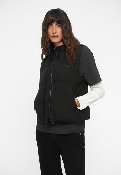 Gilet invernale nero con colletto alto, chiusura zip frontale e tasche laterali. Indossato sopra una maglietta grigia a maniche lunghe, caratterizzata da una texture liscia e opaca.