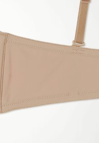 Béžový podprsenkový pás s hladkým povrchem, se plochými švy a nastavitelnými ramínky. Navržen pro pohodlí s minimálními detaily na kovových prvcích.