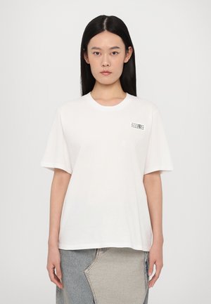 T-shirt bianco in cotone con maniche corte, scollatura rotonda e un piccolo dettaglio grafico nella zona sinistra del petto. Tessuto morbido e vestibilità rilassata.