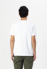 Hvit bomulls t-skjorte med korte ermer og rund hals, vist fra baksiden, med et enkelt design og en avslappet passform.