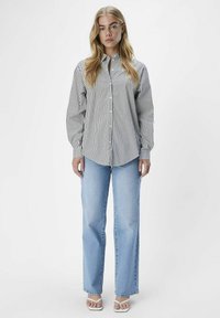 Gestreiftes button-up Hemd in Schwarz und Weiß, mit langen Ärmeln und lockerer Passform, kombiniert mit hellblauen geraden Jeans.