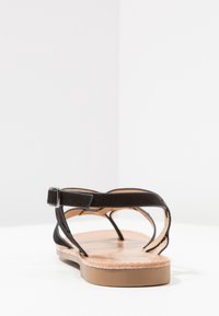 Musta nahkainen sandaali, jossa on litteä pohja, säädettävä nilkkavetoketju, avoin muotoilu ja sileä sisävuori. Pohjassa on kevyt puumainen rakenne.