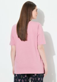 Svetle růžové tričko s krátkým rukávem, volného střihu, hladké struktury, s kulatým výstřihem a minimalistickým designem. Připárováno s kalhotami s tmavým květinovým vzorem.