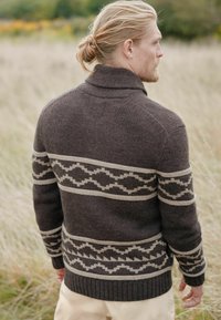 Mørkebrun sweater med høj krave, med cremefarvede zigzag-mønstre over brystet og ærmerne, ribbede manchetter og kant.
