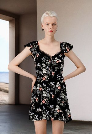 Robe noire à fleurs avec des manches volantées, bordure en dentelle et taille cintrée. Présente des motifs floraux multicolores sur l'ensemble.