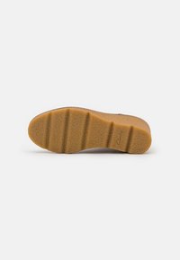 Shoe sole in light brown rubber with textured grip and Clarks brand logo visible near the heel, isolated on a white background.