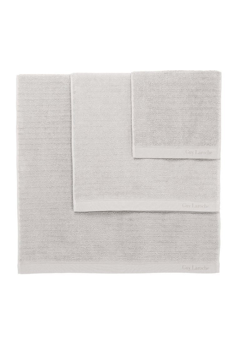 Trois serviettes grises empilées de tailles variées. Chaque serviette a une surface texturée et une bordure avec le logo "Guy Laroche".