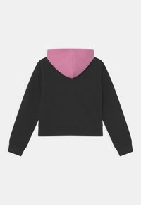 Felpa nera con fodera interna rosa, caratterizzata da una vestibilità rilassata, maniche lunghe e orlo a coste. Testura liscia con un design semplice.