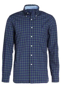 Grön och marinblå rutig skjorta med knappar, med standardkrage och långa ärmar. Har vita knappar och en liten logotyp på bröstet.