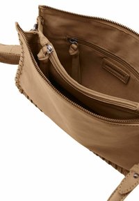 Interno di una borsa in pelle marrone chiaro con una singola tasca con zip e scomparti. Texture liscia con dettagli di cucitura lungo i bordi.