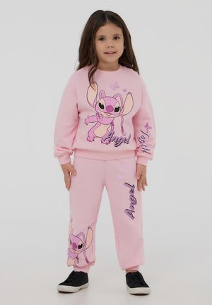 Completo in felpa rosa con pantaloni della tuta, caratterizzato da un personaggio dei cartoni animati con grandi orecchie, dettagli stampati e applicazioni a forma di farfalla. Indossate scarpe nere.