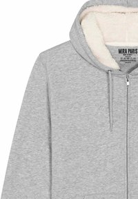 Felpa grigia con zip, dotata di un morbido rivestimento in pile color crema, cordini e un design in tessuto testurizzato. Etichetta del marchio visibile all'interno.