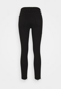 Jeans ajustados negros de cintura alta con dobladillos deshilachados y dos bolsillos traseros, mostrados sobre un fondo blanco liso.