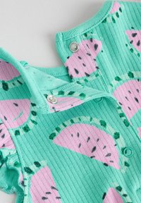 Mintgrön ribbad tyg med mönster av rosa vattenmelonbitar. Tryckknappar vid axlarna och dekorativa volanger på ärmarna.