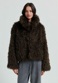 Brun, fluffig kort jacka med hög krage och lös passform. Har en texturerad yta och vida ärmar, tillverkad av ett mjukt, syntetiskt pälsmaterial.