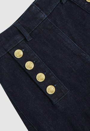 Sötét farmernadrág, magas derékkal, aranyszínű, oldalsó patent gombokkal és klasszikus öt zsebes kialakítással. A textúra sima és strapabíró.