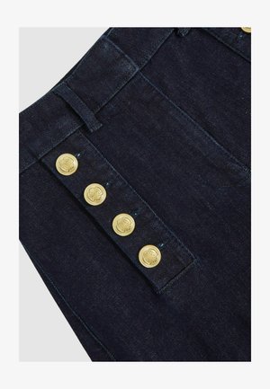 Ciemne spodnie dżinsowe z wysokim stanem, złotymi guzikami po bokach i klasycznym projektem z pięcioma kieszeniami. Materiał jest gładki i wytrzymały.
