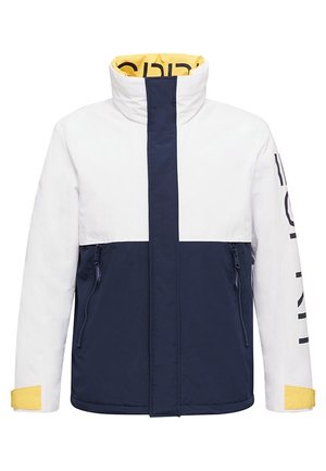 Weiß-navyblaue Jacke mit gelbem Innenkragen, Reißverschlusstaschen vorne und schwarzem Text auf dem rechten Ärmel.