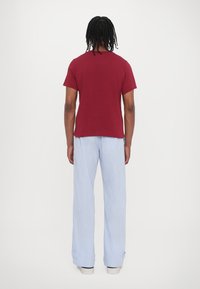 Maroon short-sleeve t-shirt paired with light blue striped wide-leg pants. The fabric appears soft; pants feature cuffs at the ankles.