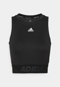 Top corto atlético negro hecho de una tela elástica. Cuenta con un escote redondo, diseño sin mangas y una banda elástica con "ADIDAS" impresa en ella.