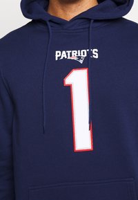 Sudadera con capucha navy con el texto "PATRIOT'S" y el gran número blanco "1" contorneado en rojo. Cuenta con un bolsillo frontal y cordones.