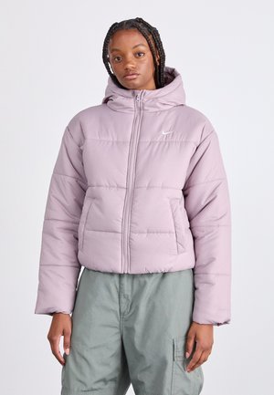 Doudoune lilas avec capuche, dotée d'une fermeture éclair à l'avant et de panneaux cousus. Logo blanc en haut à gauche. Assortie à un pantalon vert clair.